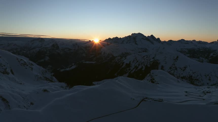 A mountain range covered in snow and ice with the sky and clouds in the background