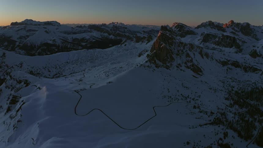 A zigzag trail runs along a snow covered mountain