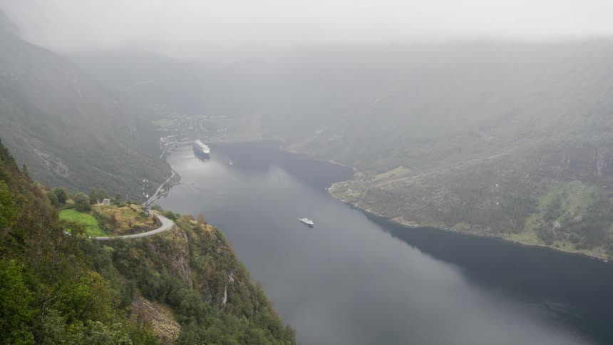 Aerial view of boats and ferries leaving port on a lake between the mountains under the mist