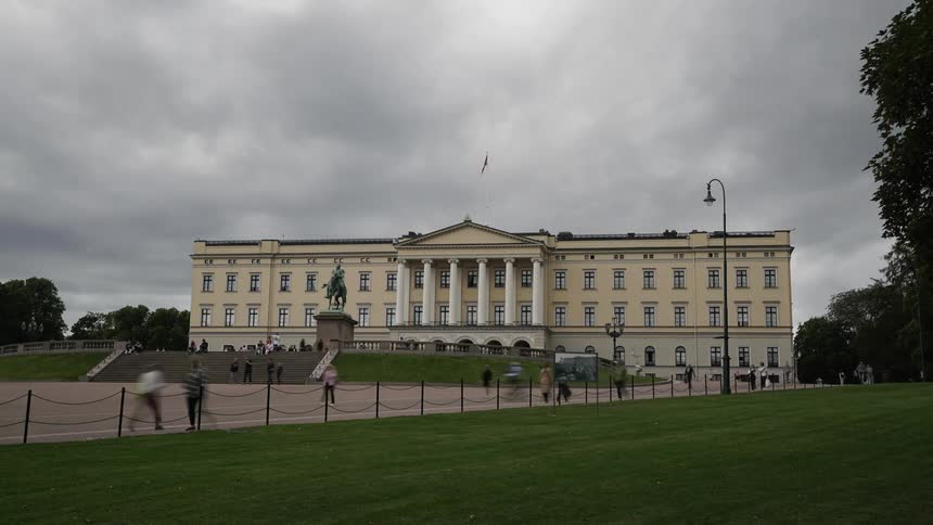 A building with a statute and pedestrians in the foreground with the sky and clouds in the background
