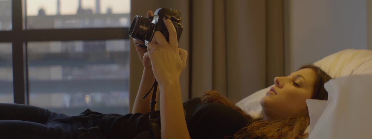 A woman lays down using her camera