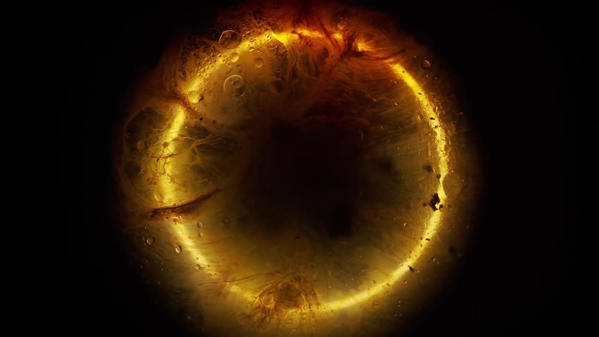 Yellow glowing ring surrounded by liquid rotates as colored tendrils flow