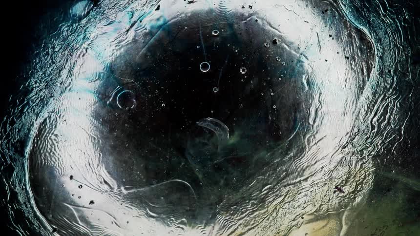 Underwater footage of water flowing on the surface of a frozen lake