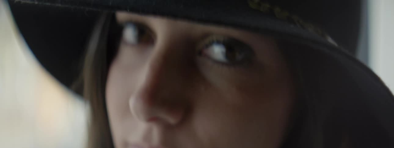 Woman wearing a hat turning her head and looking into the camera