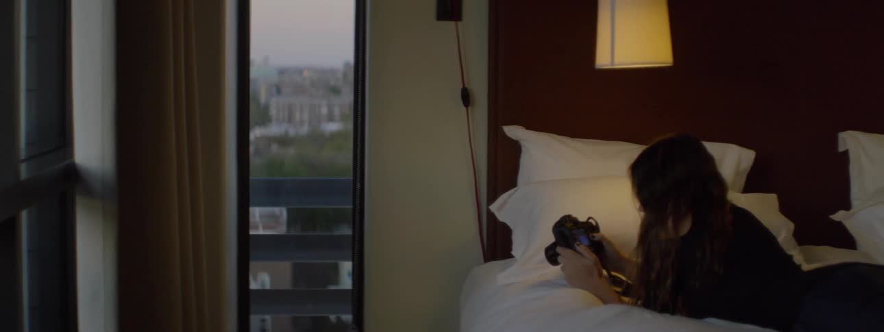 Girl laying on a bed looking at a camera