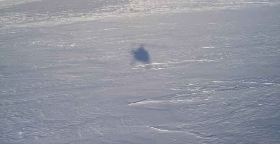 Shadow of a flying helicopter flying over the snow covered landscape