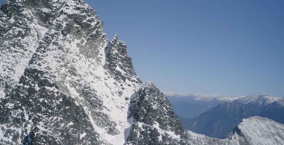 A mountain range covered in snow and ice with the sky and clouds in the background