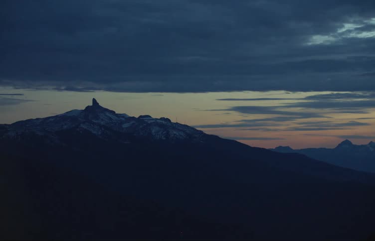 A mountain range covered in snow and ice with the sky and clouds in the background