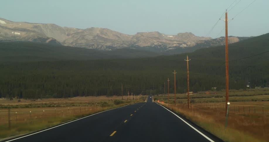 Traveling on a road lined with utility poles and mountains on the horizon
