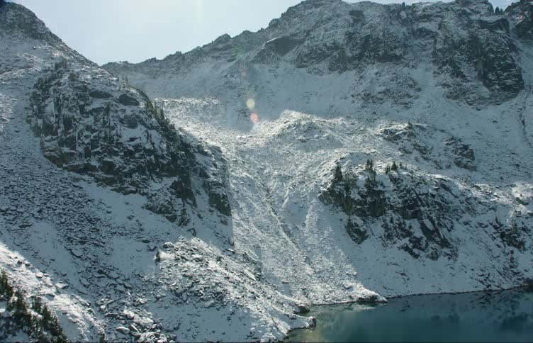 Aerial view of a lake near the snow covered slopes of a mountain range