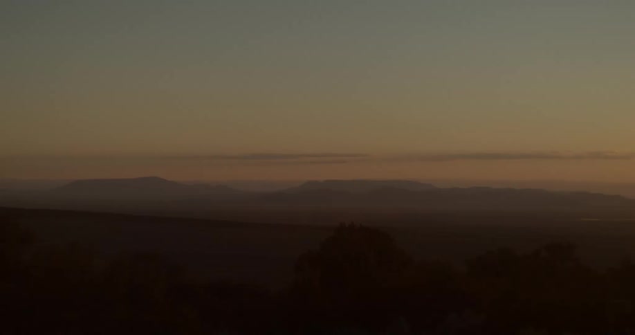 Silhouette of a mountain range surrounded by fog under the dark evening sky
