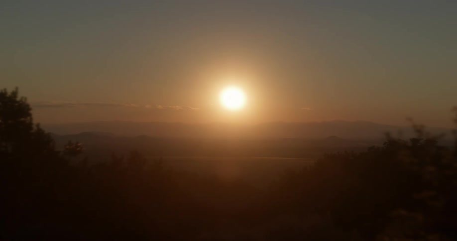 Sun shines from hazy sky onto misty landscape
