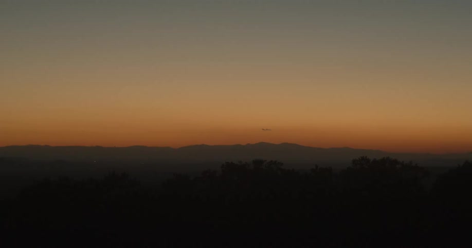 A landscape with trees a mountain range the sky and clouds in the background