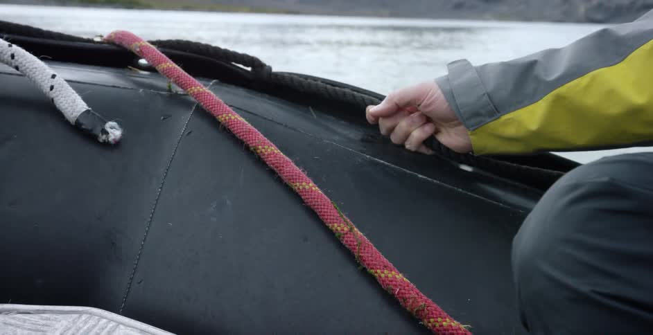 Person holding on in a small boat moving slowly on water