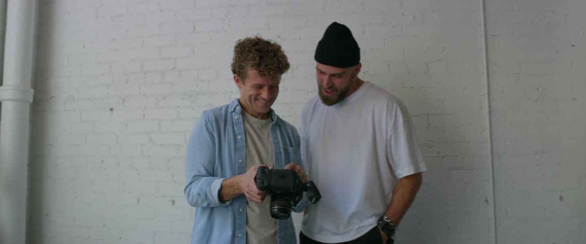 Man smiles and half hugs photographer as they view pictures on camera