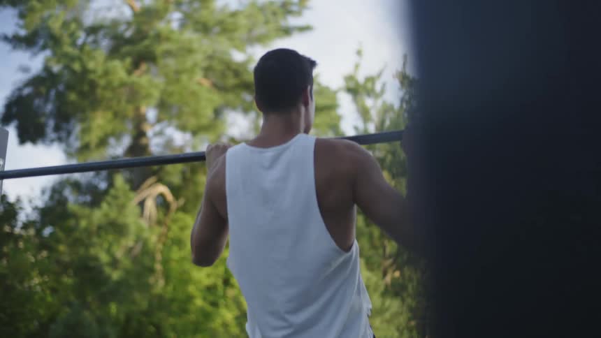 A man is doing pull ups in the park