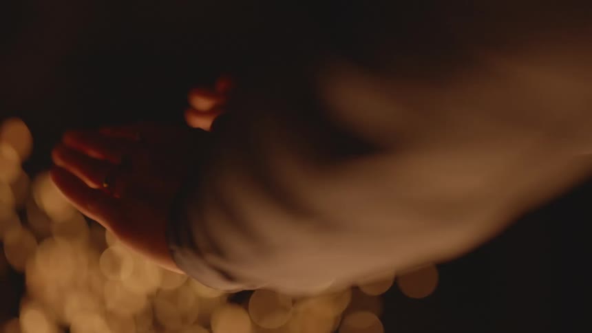 Person wearing long sleeves rubs their hands before reaching them out fire as sparks rise
