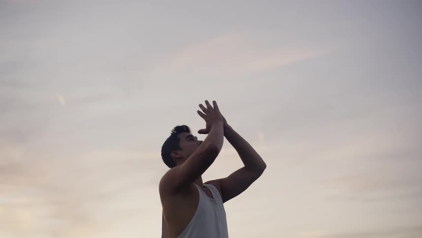 A man practices yoga outdoors in the evening