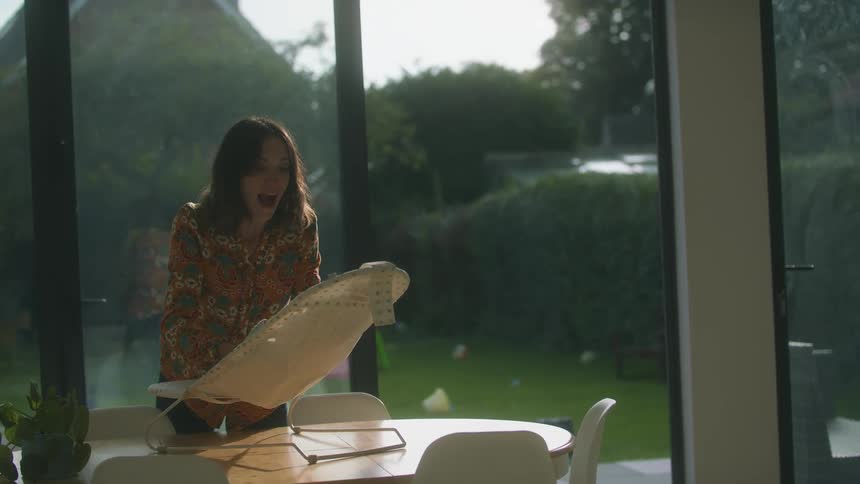 A mom lifts and adjusts her baby in a table top swing seat making faces and smiling at him