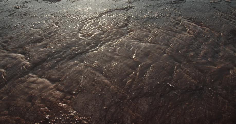 Shallow clear water flowing over the rocky surface at morning