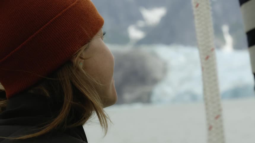 Woman wears knit hat while looking at snow covered landscape