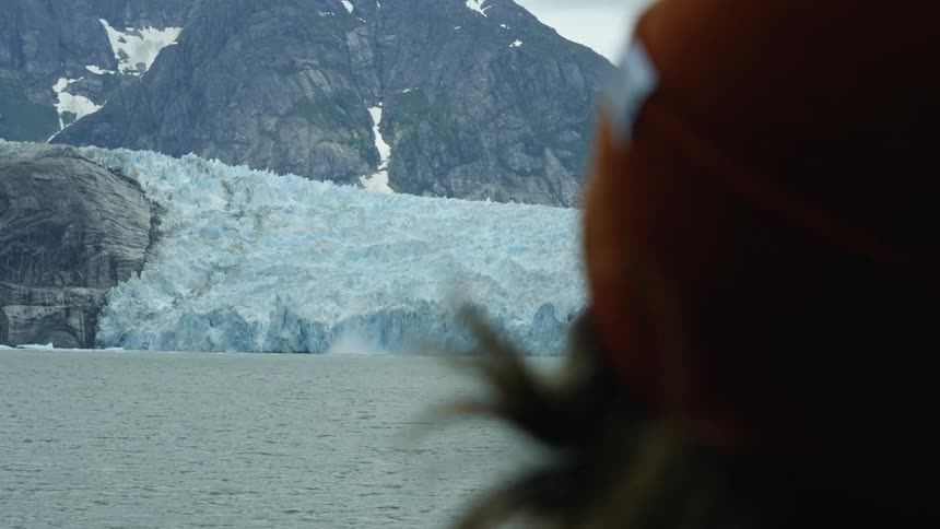 A person is looking over the river to the ice lined mountain