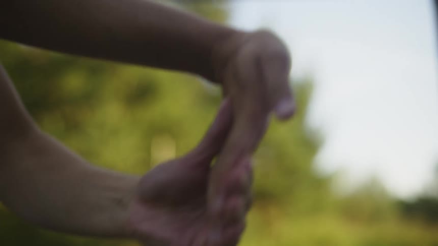 Young man wearing white undershirt stretches his hands in the countryside at morning