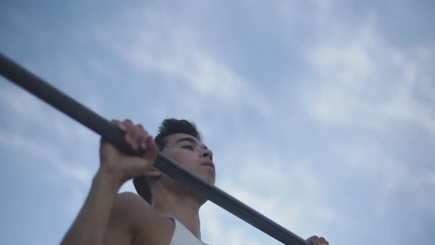 A man doing pull ups on playground equipment outside
