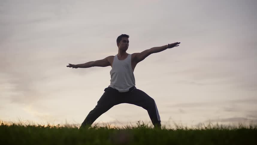 A man is doing yoga in the grass