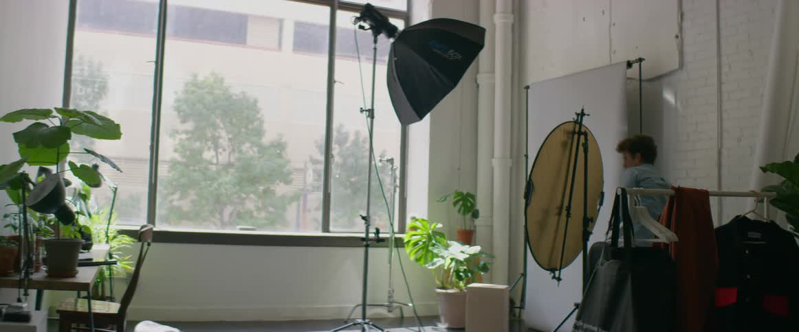 Man walks around photography studio plugging in light as his dog sleeps on floor