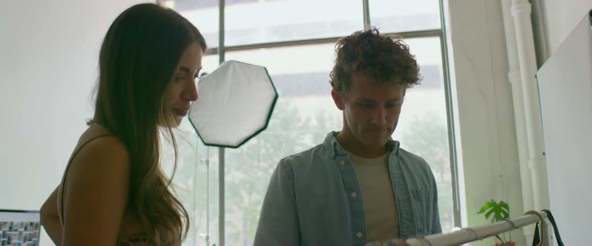 A man and woman are looking through a rack of clothing