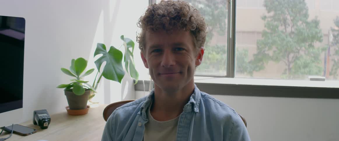 Young man sitting at a desk smiles while looking at the camera