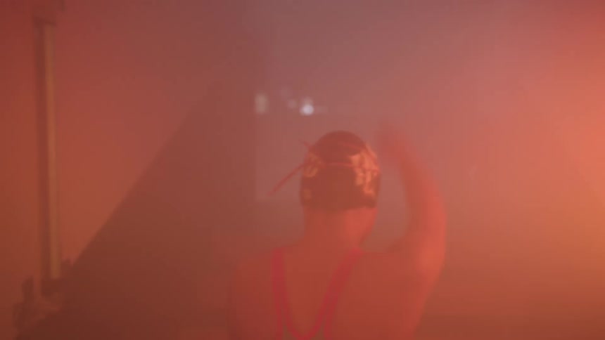 A woman with a bathing suit and a swimming cap walking through a corridor with flashing lights