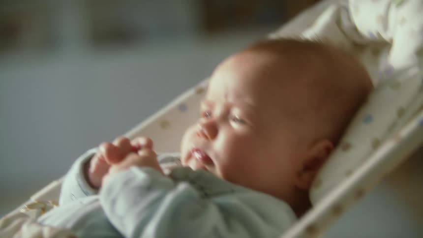 Baby being rocked in cradle looks around