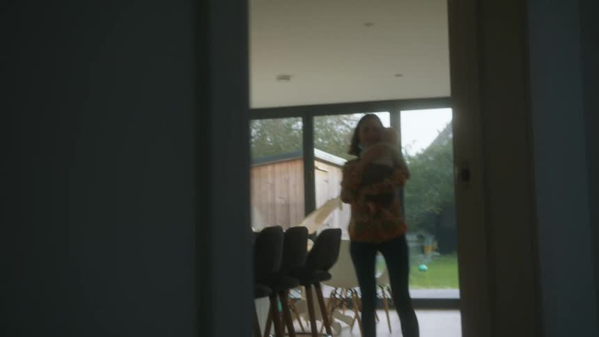 Mother carrying a toddler in her arms walking at home