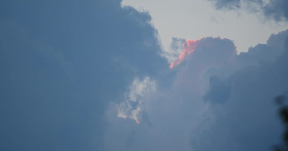 The sun shines on cumulus clouds as darker clouds move over them