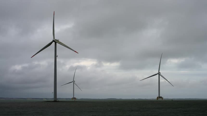 Wind turbines spinning under the white clouds on the field