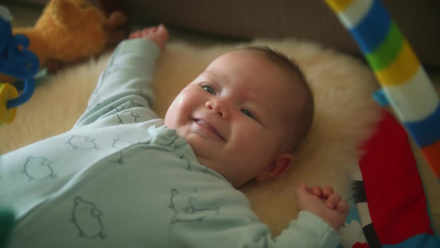 Baby boy with blue eyes lies down in baby gym