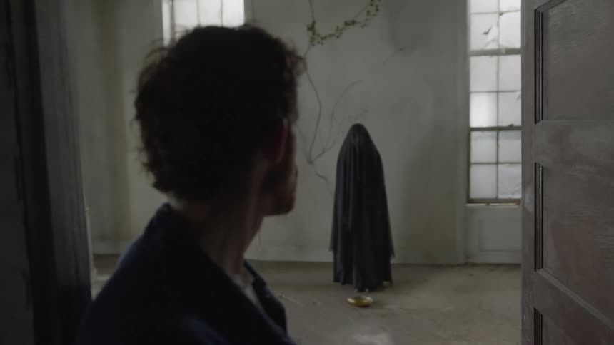 Red haired man with beard turns to look at woman wearing covering who bends to pick up golden plate