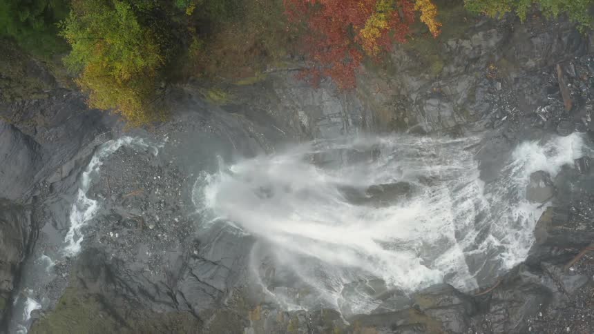 Water flows down waterfall past trees with fall foliage