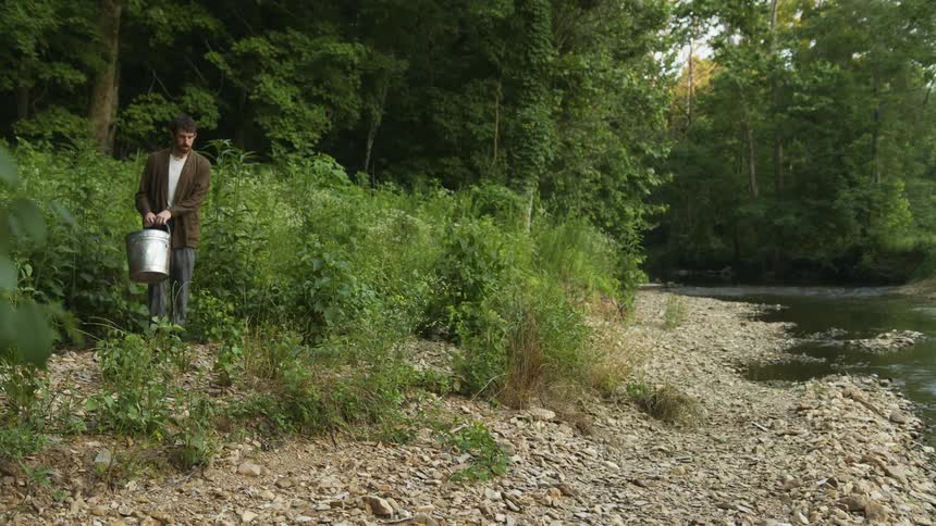 A man carries a bucket to the stream