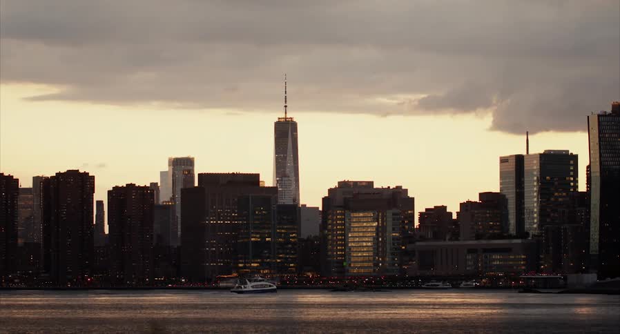 A small yacht sails past downtown at sunset
