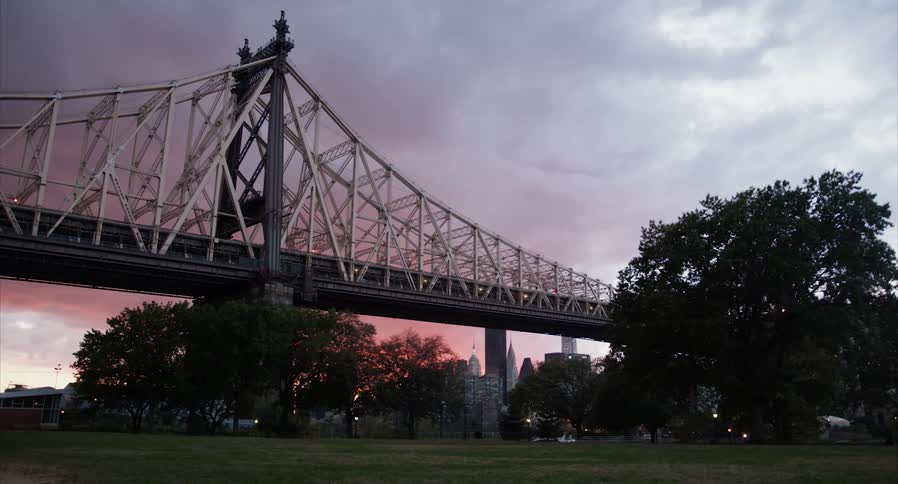 Steel bridge in front of the city skyline under the red clouds at sunset