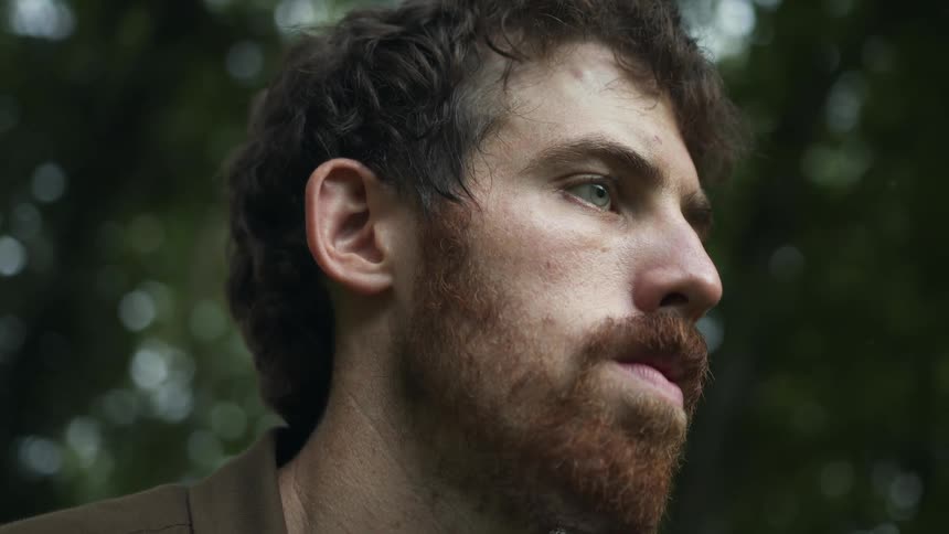 A man is staring forward in the forest