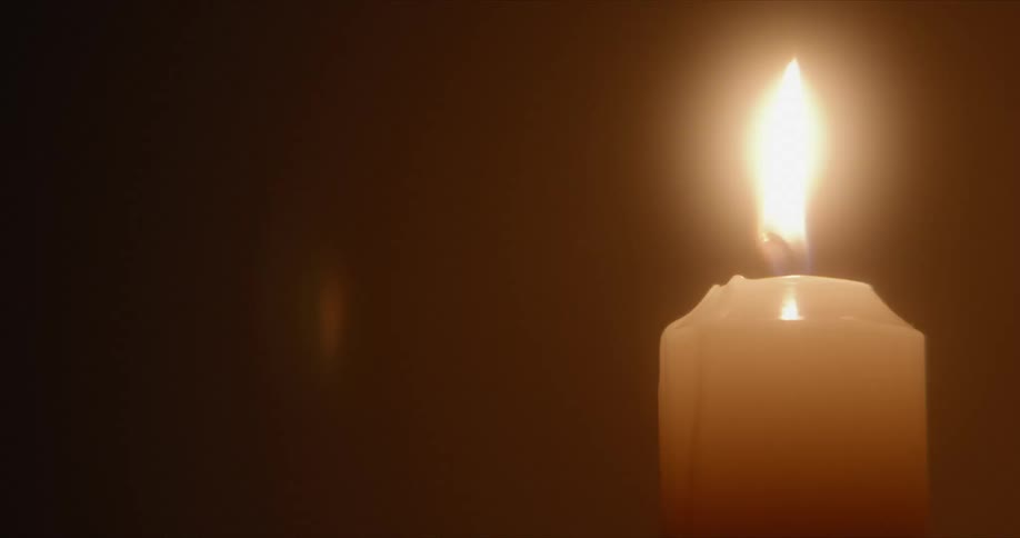 The flame of a candle is glowing in the darkness