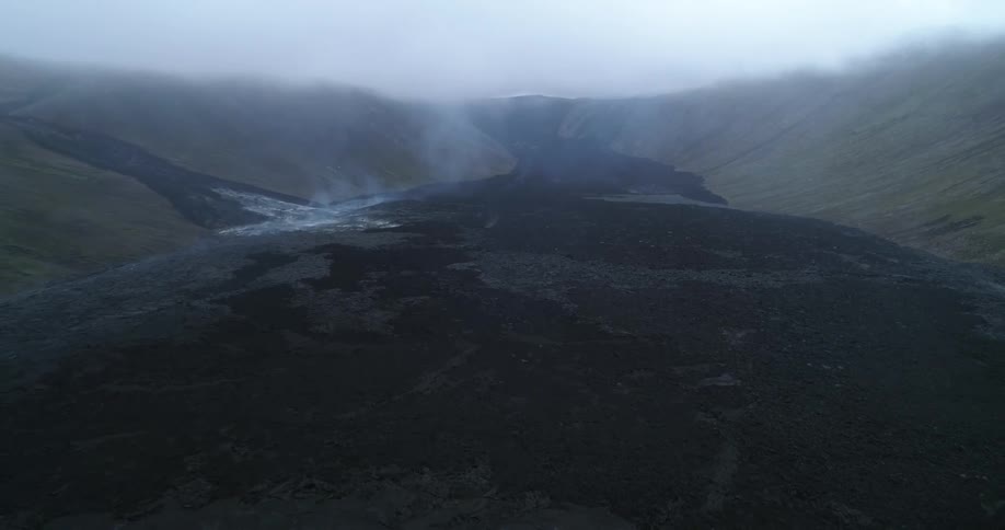 Smoke rises from cooling lava flow in valley between slopes