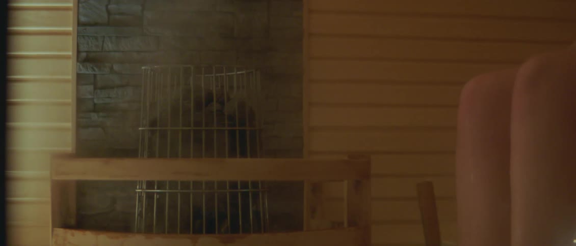 A person in a sauna using a scoop to put water on hot rocks