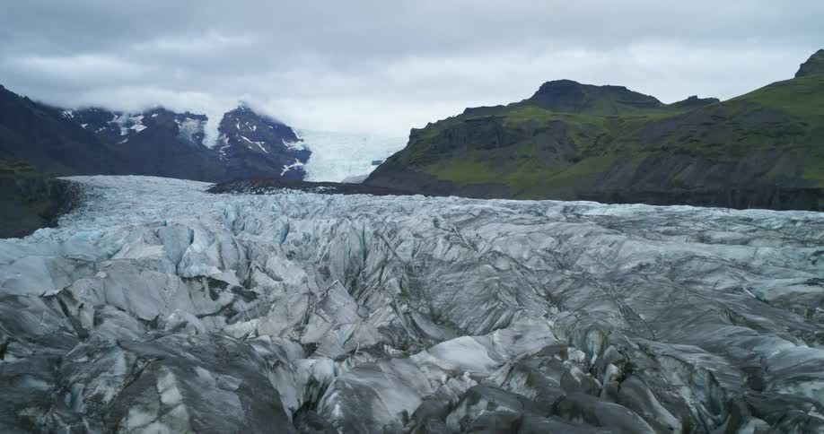 A large glacier in between mountains in the arctic wilderness