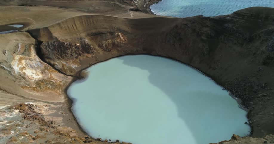An aerial view of a large pools of water surrounded by rocky and sandy terrain in the daytime
