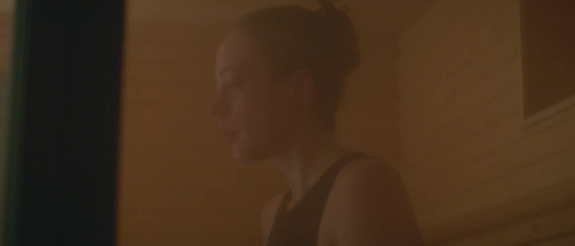 A woman wearing a black tank top shirt is standing in a room and crying